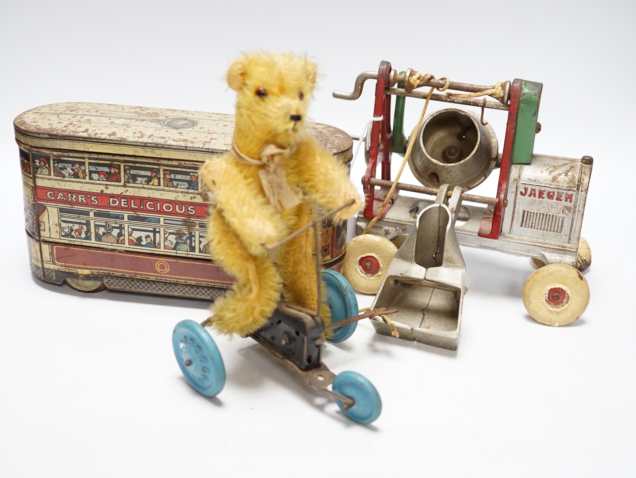 Three tinplate/cast iron toys; a Jaeger cast iron concrete mixer, a Carr’s tinplate biscuit tin in the form of a tram, and a clockwork teddy bear on a tricycle, tram 22cm long